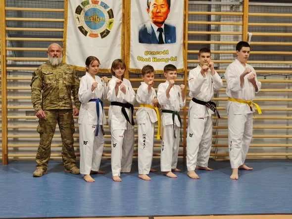 Zawodnicy TKD Dźwirzyno w dobokach po egzaminie na stopnie kup, w tle flaga ITF